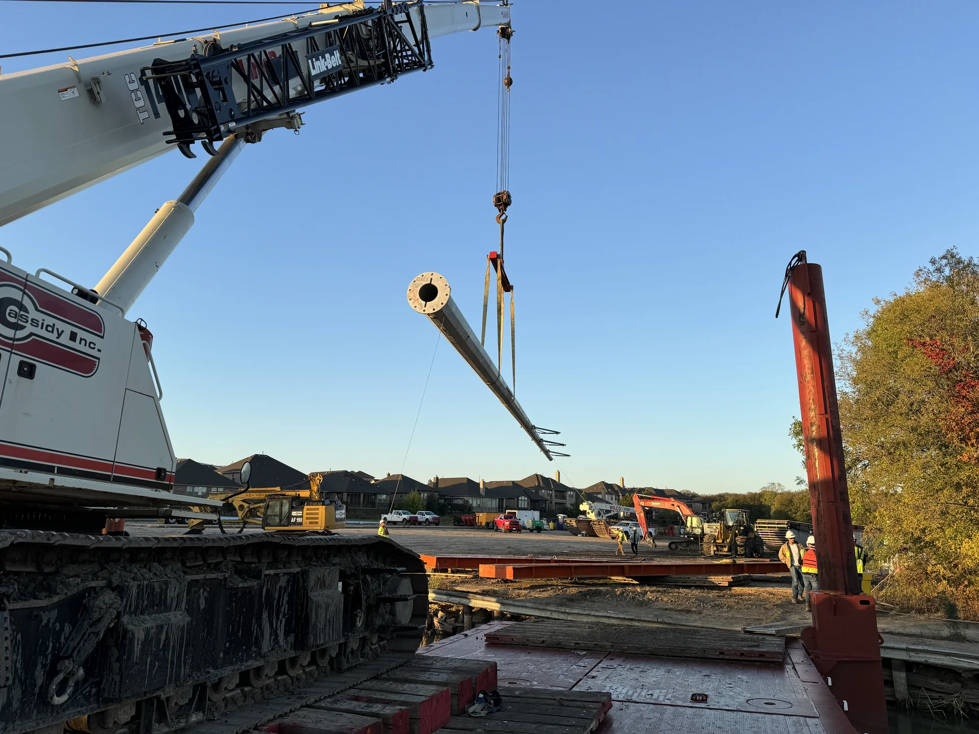 Crane lifting a steel pole for installation.