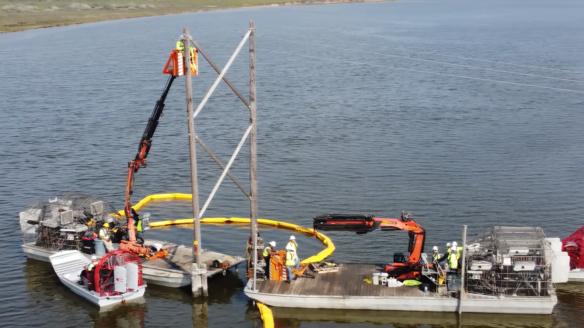 Airboat crews working around a transmission structure in open water.